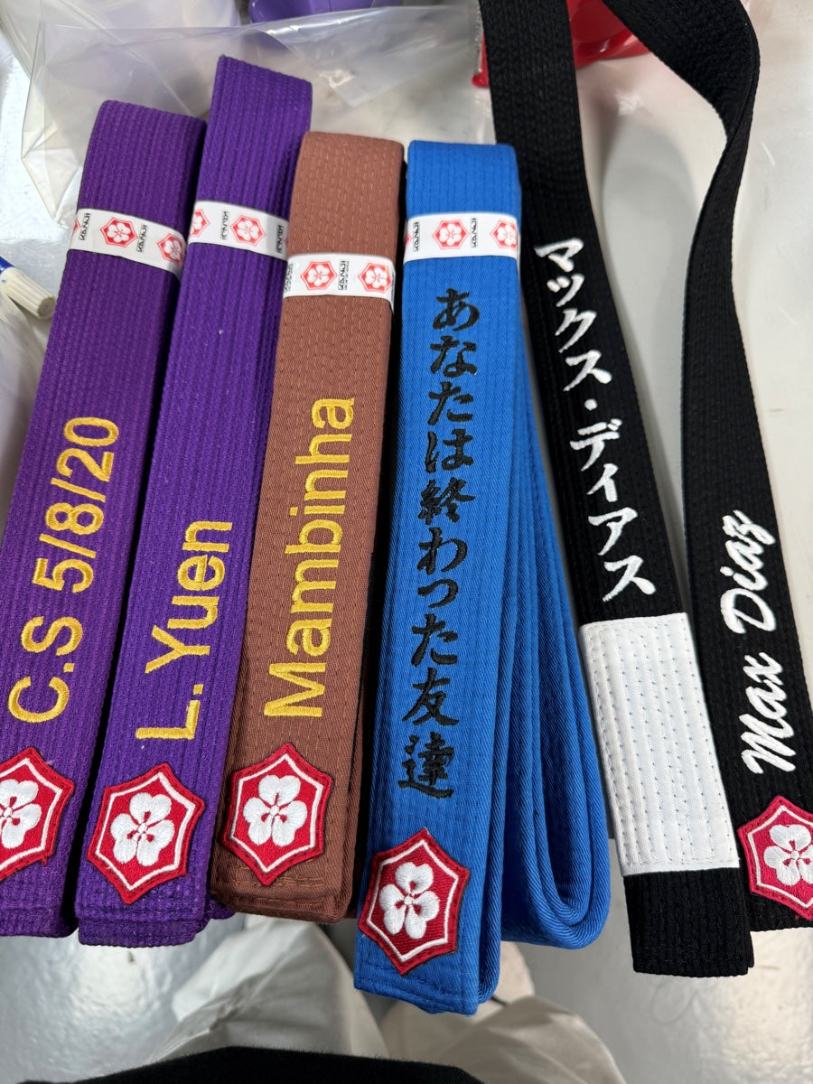 色の異なる帯に施した氏名と日本語の刺繍